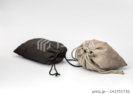 Mystery and uncertainty concept showing two closed drawstring pouches made of soft black and beige suede fabric, tightly tied with cords and hiding unknown contents that may be highly valuable Mystery and uncertainty concept showing two closed drawstring pouches made of soft black and beige suede fabric, tightly tied with cords and hiding unknown contents that may be highly valuable 143701730