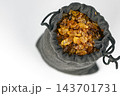 Close-up top view of glittering golden brown caramel rock sugar crystals revealed inside an opened gray fabric drawstring pouch, mystery bag concept of hidden treasure or worthless contents on white 143701731