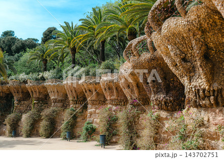 Stone colonnade with palm trees and tourists on the Viaduct of Park Guell in Barcelona 143702751