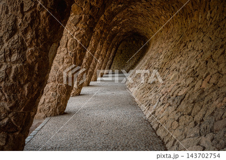 Empty vaulted stone gallery with slanted columns in Park Guell Barcelona 143702754