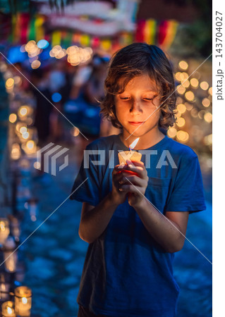 Child sharing a reflective moment with a votive candle at a remembrance event. Child sharing a reflective moment with a votive candle at a remembrance event. 143704027
