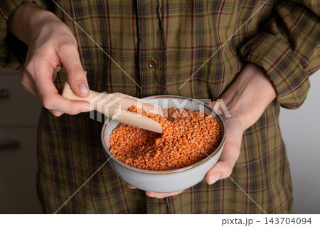 Hands Holding Bowl of Red Split Lentils with Wooden Scoop Hands Holding Bowl of Red Split Lentils with Wooden Scoop 143704094