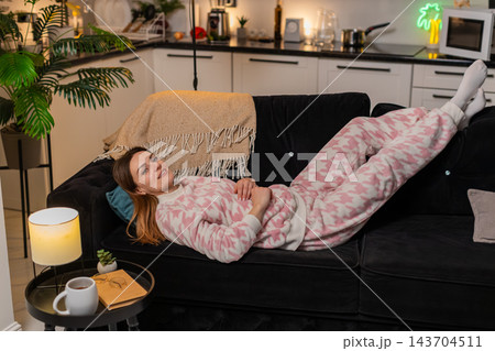Adult woman relaxes at night smiles carefree mood lifts legs enjoys quiet rest comfort peace happy Adult woman relaxes at night smiles carefree mood lifts legs enjoys quiet rest comfort peace happy 143704511
