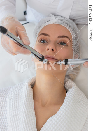 Beautician doctor makes woman micro currents face therapy using electrical impulses in spa salon Beautician doctor makes woman micro currents face therapy using electrical impulses in spa salon 143704821