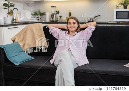 Young woman unwinds and rests takes slow breaths and finds calm posture with gentle smile and ease Young woman unwinds and rests takes slow breaths and finds calm posture with gentle smile and ease 143704829