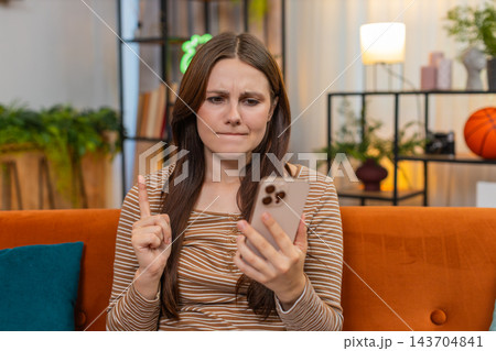 Young woman gets app error on smartphone frowns shows no no finger and taps retry after game freeze Young woman gets app error on smartphone frowns shows no no finger and taps retry after game freeze 143704841
