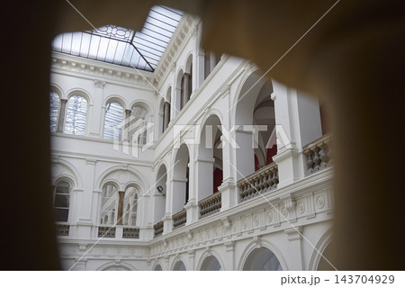 View through dark archway toward interior courtyard with arcades, balustrades and glass roof View through dark archway toward interior courtyard with arcades, balustrades and glass roof 143704929