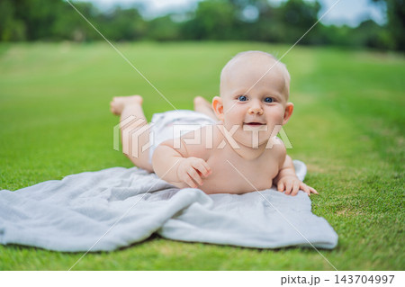 Curious baby exploring outdoor surroundings from a soft blanket. Curious baby exploring outdoor surroundings from a soft blanket. 143704997