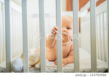 Curious infant exploring the cot during independent awake time. Curious infant exploring the cot during independent awake time. 143704998
