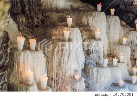 Burning votive candles above thick layers of melted wax in a devotional display. Burning votive candles above thick layers of melted wax in a devotional display. 143705001