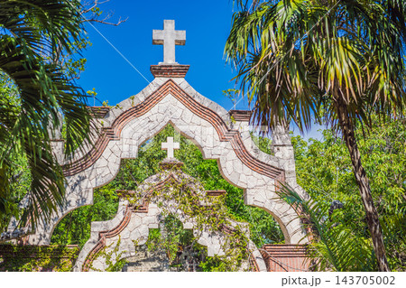 Stone chapel facade with a cross surrounded by tropical vegetation. Stone chapel facade with a cross surrounded by tropical vegetation. 143705002