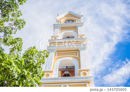 Yellow clock tower framed by dense tropical vegetation. 143705005