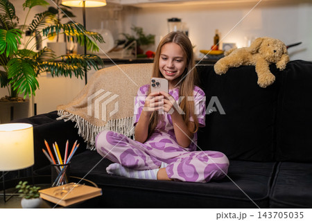 Teenager girl texting reply after happy message from friend on smartphone smiling chat app at night 143705035