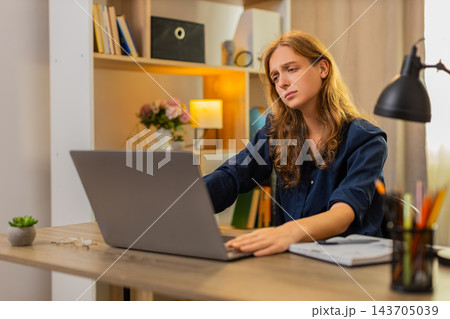 Young woman on home table looks at laptop feeling upset after error message and failed online result Young woman on home table looks at laptop feeling upset after error message and failed online result 143705039