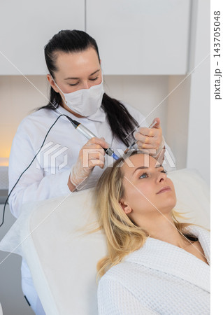 Trichologist doing woman improve hair growth procedure, dermapen microneedling, vitamin injections 143705048