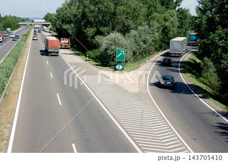 Highway Exit with Traffic, Trucks, Cars and Green Road Sign Highway Exit with Traffic, Trucks, Cars and Green Road Sign 143705410