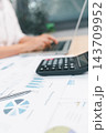 Financial report with charts, pen, and calculator on an office desk while a professional uses a laptop, representing accounting, budgeting, analytics, finance, planning, and business research. 143709952