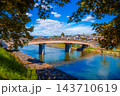 Bridge spans the Uji River in Uji City, Kyoto Prefecture, Japan.With maple leaves changing color in the foreground and the sky in the background. 143710619