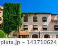 Beautiful windows with green plant on building of Venetian-style Italian village landscape on mountain with blue sky background 143710624