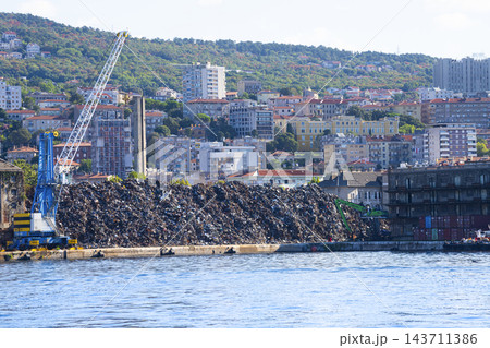 A large pile of scrap metal is being processed by cranes at the harbor  of Rijeka, Croatia 143711386