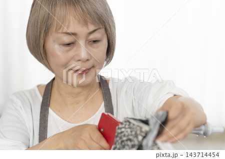 リビングで趣味のDIYでドールチェアーをリメイクするシニア女性 リビングで趣味のDIYでドールチェアーをリメイクするシニア女性 143714454