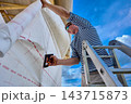 Nonwoven polypropylene fabric is positioned by construction worker over timber wall framing to form wind and water resistant membrane. 143715873