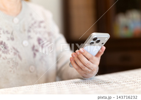 家のリビングでスマホを見るミドル・シニア女性 143716232