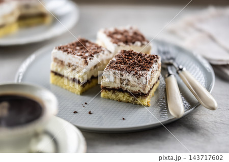 Delicious layered cakes with cream, bananas, and fluffy whipped cream served on an elegant plate. The top of the desserts is sprinkled with finely grated dark chocolate 143717602