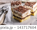 Delicious layered cakes with cream, bananas, and fluffy whipped cream served on an elegant plate. The top of the desserts is sprinkled with finely grated dark chocolate 143717604