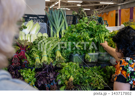 Shoppers Selecting Fresh Green Vegetables at Busy Farmers Market Produce Stall 143717802