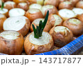 Green shoots emerge from a cut onion bulb among other bulbs in a market display, with no time of day shown 143717877