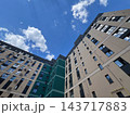 New development apartment buildings rise around an inner courtyard in a city, viewed from below during the day under a blue sky 143717883