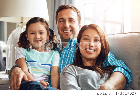 Interracial parents, girl and portrait on sofa with smile, hug and relax with care, diversity and happy in family home. Father, mother and daughter with embrace, connection and love on lounge couch Interracial parents, girl and portrait on sofa with smile, hug and relax with care, diversity and happy in family home. Father, mother and daughter with embrace, connection and love on lounge couch 143717927