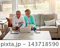 Senior couple, documents and laptop on couch with discussion, smile and point for taxes in home. Old man, woman and computer with paperwork for compliance, reading and investment report with solution 143718590