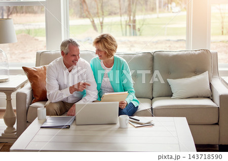 Senior couple, documents and laptop on couch with discussion, smile and point for taxes in home. Old man, woman and computer with paperwork for compliance, reading and investment report with solution 143718590