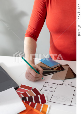 Interior designer presents selected material samples beside a floor plan in studio Interior designer presents selected material samples beside a floor plan in studio 143719427