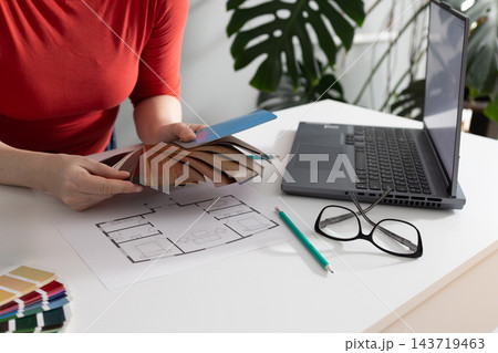 Designer evaluating warm wood flooring samples in a design studio Designer evaluating warm wood flooring samples in a design studio 143719463