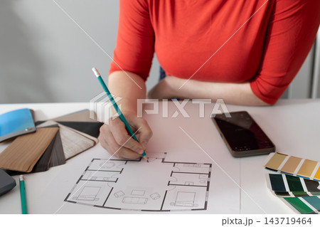 Interior designer annotating a floor plan at a design desk during home renovation planning Interior designer annotating a floor plan at a design desk during home renovation planning 143719464