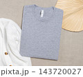 Heather grey folded t-shirt mockup near knitted cardigan and palm leaf, template for print on demand 143720027
