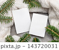 Blank vertical cards mockup near green fir branches and white knitted blanket. Rustic holiday scene 143720031