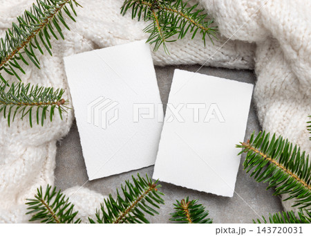 Blank vertical cards mockup near green fir branches and white knitted blanket. Rustic holiday scene Blank vertical cards mockup near green fir branches and white knitted blanket. Rustic holiday scene 143720031