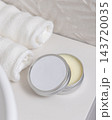 Open cosmetic body butter tin with metal lid near white towels in bathroom, round blank label mockup 143720035