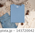 Falded washed light blue t-shirt mockup near rustic Christmas decor, flat lay. Holiday template 143720042