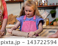 Young chef practicing pastry skills with dedicated expression in kitchen, Miniature assistant skillfully rolls dough with determination amidst pantry setting for baking lesson Young chef practicing pastry skills with dedicated expression in kitchen, Miniature assistant skillfully rolls dough with determination amidst pantry setting for baking lesson 143722594