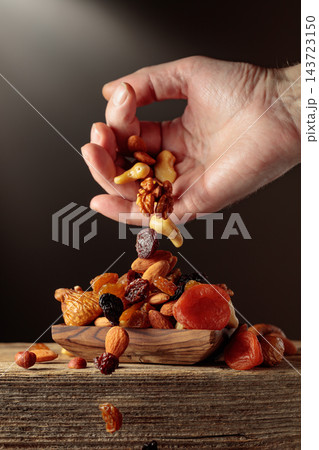 Mix of dried fruits is poured in a wooden dish. Mix of dried fruits is poured in a wooden dish. 143723150