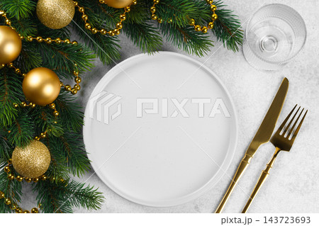 Christmas table setting with empty white plate, golden cutlery and holiday decor on gray background 143723693