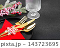 Festive Christmas table setting, dinnerware. Black plate and gold cutlery in red star shaped holder 143723695