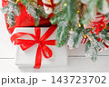 Red wrapped gift boxes, presents under festive Christmas tree with lights and holiday decorations 143723702
