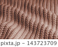 Soft brown knitted sweater texture with chunky yarn and raised stitches, waves and gentle folds 143723709