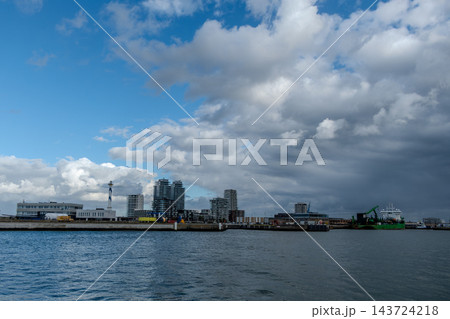 City skyline over the sea at the harbor under a cloudy sky City skyline over the sea at the harbor under a cloudy sky 143724218